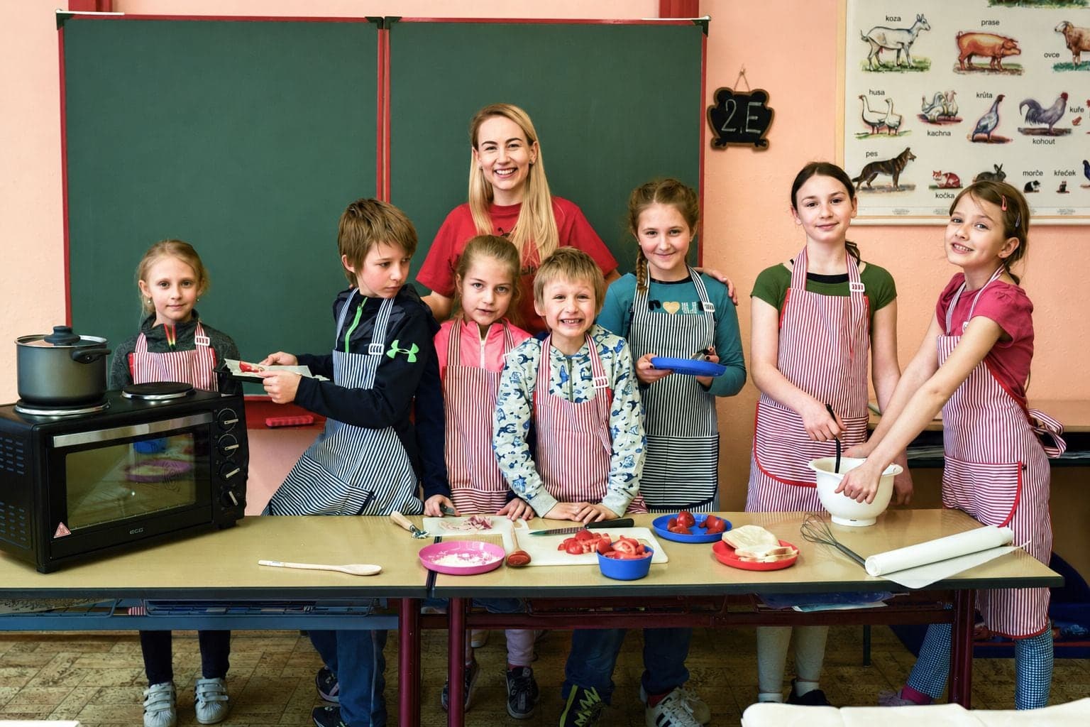 Prowadząca KółkoKids z dziećmi na zajęciach kulinarnych w szkolnej klasie